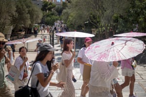 Athens, Greece Tourists protect themselves from the sun near the Acropolis hill