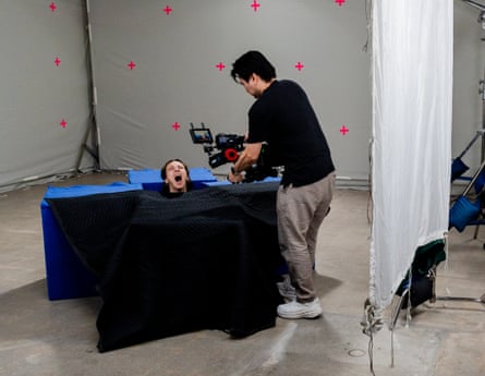 Tori Thomas, inside a box with just her head showing, screams as a camera operator films her.