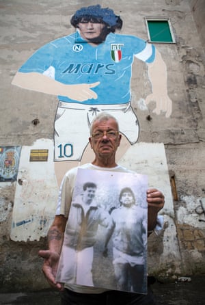 Antonio “Bostìk”, a barman, posing in front of the Maradona mural, shows the photo in which as a young fan, he approached the captain on the sidelines