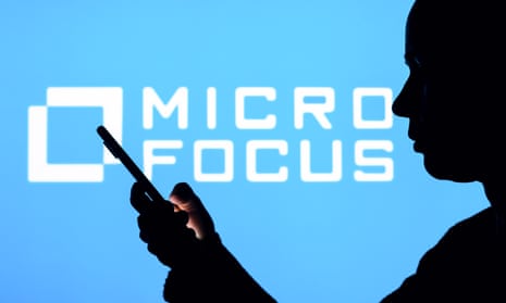 Micro Focus logo behind person looking at phone