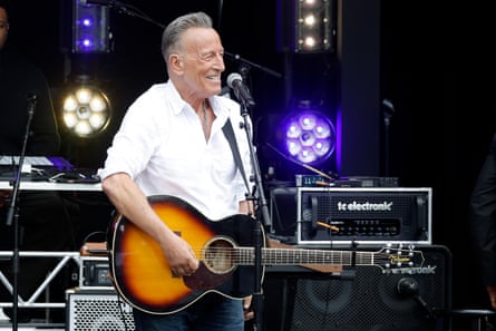 Smiling man in white collared shirt playing acoustic guitar.