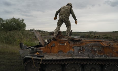 A Ukrainian serviceman stands atop a destroyed Russian vehicle in a retaken area near the border with Russia in Kharkiv region, Ukraine.