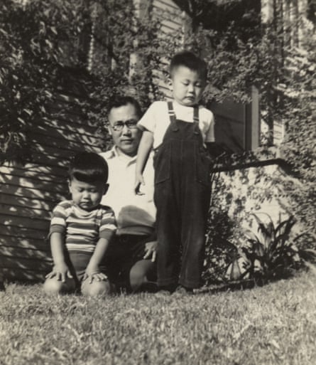 George (right), about five, and his brother, Henry, with their father on the grass outside a house