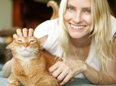 She strokes a ginger cat, smiling