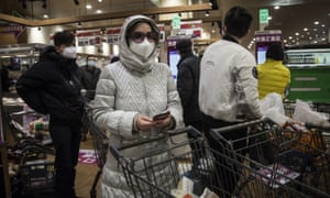 Residents wear protective mask as they line up to pay in the supermarket in Wuhan.