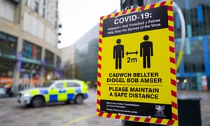A Covid-19 warning sign in Cardiff. From Saturday, four people from two households will be able to meet outdoors, outdoor sports facilities can reopen, and indoor care home visits will restart for single designated visitors. Photograph: Matthew Horwood/Getty Image