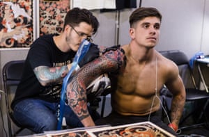 A tattoo artist works on a man’s tattoo International Tattoo Festival