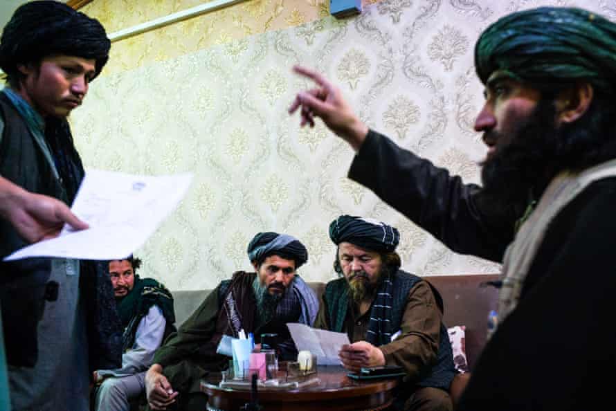 Abu Idrees, centre, the former Taliban police chief of Mazar-i-Sherif, examines documents while one of his aides issues a summon.