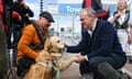Steve Darling crouching next to his dog while Ed Davey shakes the dog's paw