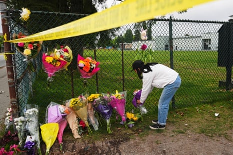 a woman bends over to place flowers at a memorial site