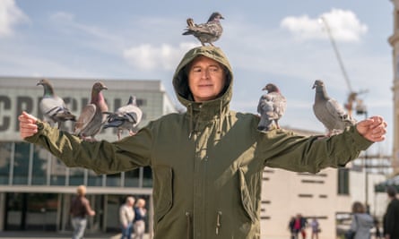 In the new Full Monty TV series, dressed in a khaki trenchcoat, standing like a scarecrow, pigeons on his arms and one on his head.