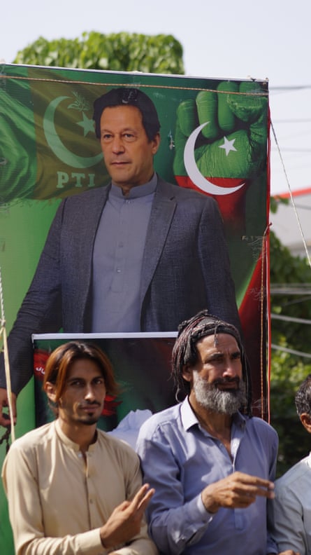 Two marchers carry a banner showing a portrait of Imran Khan
