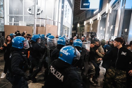 Youth protesters clash with police in Piazza del Duomo. Some of the glass windows of the shops behind have been boarded-up.