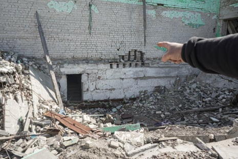 An arm pointing to a low entrance at the bottom of a building