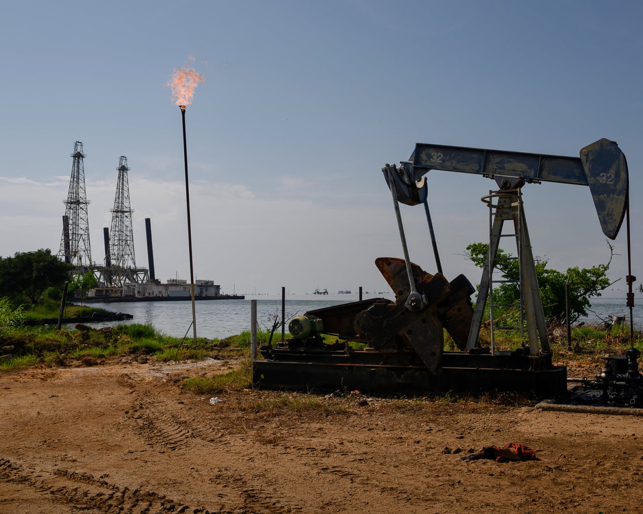 An oil pumpjack near a refinery