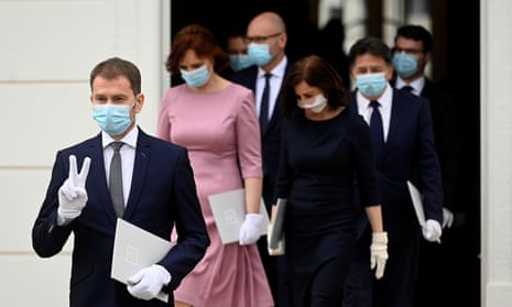 Igor Matovič, wearing a protective face mask, flashes a V-sign as he walks to pose for a group photo with newly appointed members of the Slovak government in Bratislava.