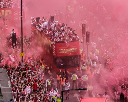 Arsenal players show off the Premier League trophy as their bus makes its way on to Holloway Road