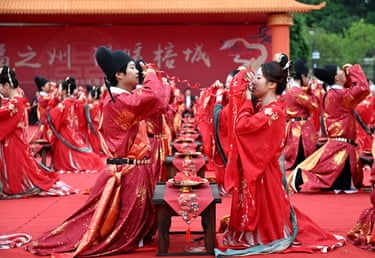Couples kneeling facing each other in red traditional robes