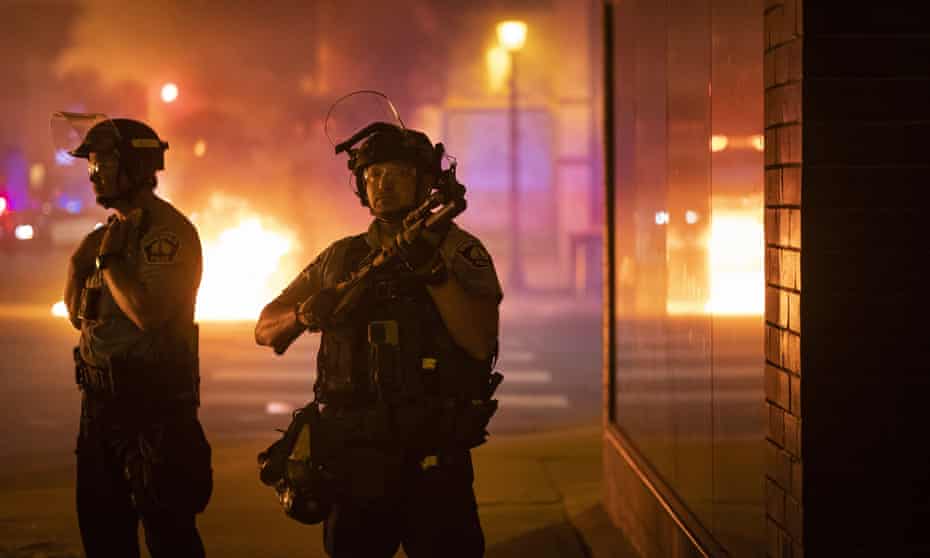 Police stand guard after protesters set fire to dumpsters after a vigil was held for Winston Boogie Smith Jr on 5 June.
