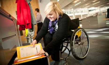 Young disabled woman in a wheelchair filing documents in a modern office