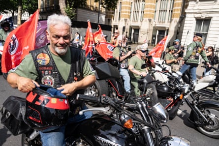 David Holmes holding a motorbike helmet amid a pack of parked bikers