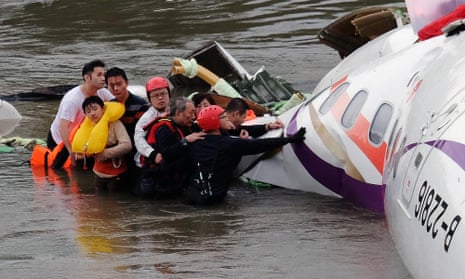 Rescue personnel help passengers as they wait to be transported to land from the wreckage of a TransAsia ATR 72-600 turboprop plane that crash-landed into the Keelung river outside Taiwan’s capital Taipei.