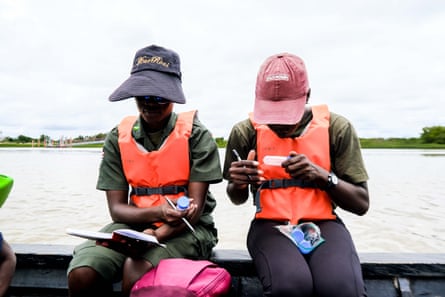 Two people sit on the side of a boat labelling test tubes