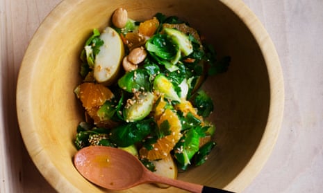 colourful Brussels sprout, apple and clementine salad in a wooden bowl.