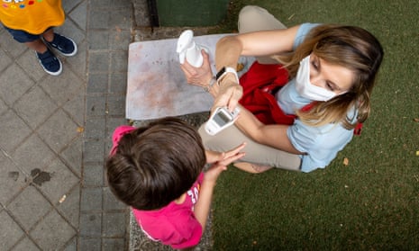 A child has her temperature checked before entering a preschool in Spain. 