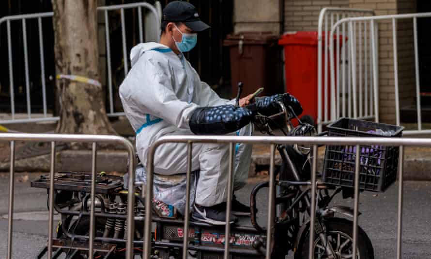 A man in protective gear rides a scooter on the street in Shanghai.