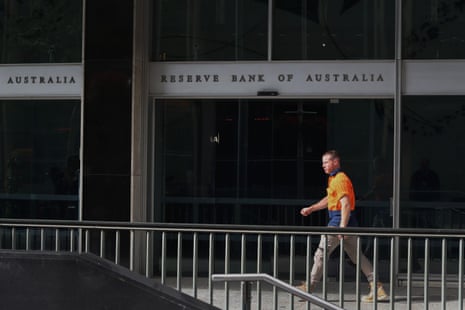 A pedestrian wearing orange hi-vis moves past the Reserve Bank of Australia building in Sydney