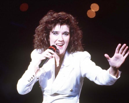 Céline Dion wearing all white singing into a microphone