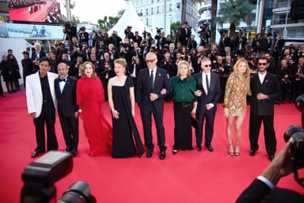 Catherine Deneuve (4th from right) and fellow cast and crew stand in a line on a red carpet surrounded by photographers