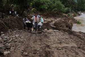 Residents carrying their belongings walk on a road damaged by flood as they evacuate from the Langjiayu village after heavy rains. The floods have forced tens of thousands to evacuate.