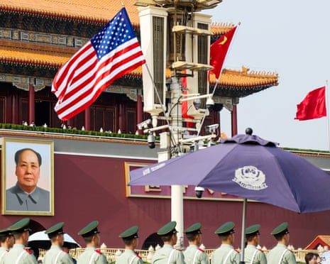 Paramilitary officers in uniform stand in formation beneath American and Chinese flags