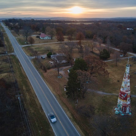A car passes a large roadside totem pole