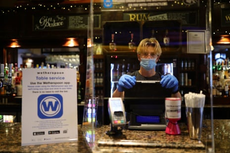 A member of staff in PPE waiting to serve drinkers at the reopening of Wetherspoons’ Toll Gate pub, in Hornsey, north London.