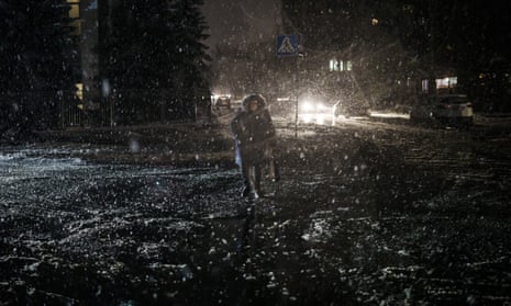 Una mujer cruza la calle durante una nevada, mientras continúan los cortes de energía en Kyiv.