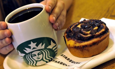 a cup of starbucks coffee in a mug sits next to a pastry
