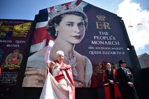 A woman playing the role of the Queen waves to the crowd at the unveiling of a new mural in honour of the jubilee on Shankill Road, Belfast