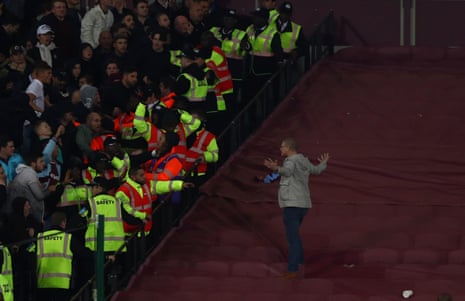 A Chelsea fan gets past the police line and walks over to goad the West Ham fans.