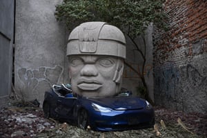 An artwork by Chavis Mármol of a Tesla 3 car being crushed by a nine-tonne Olmec-inspired head