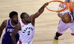 Kawhi Leonard dunks as Joel Embiid looks on