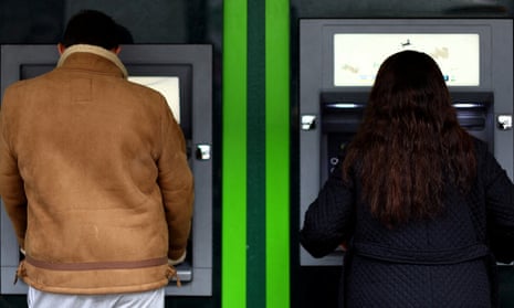Two people using cashpoints