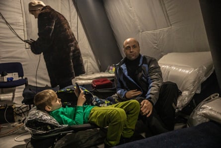Ruslan Vorona, a local Kyiv resident, together with his eight year-old son, Oleksii, sheltering and charging their phones in an insulated tent set up by the emergency services.