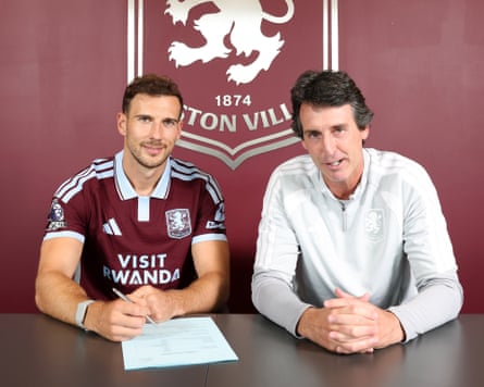 Leon Goretzka sits at a desk signing his Aston Villa contract alongside the club’s manager Unai Emery