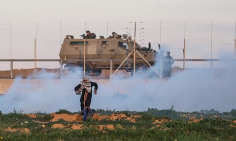 A Palestinian demonstrator and Israeli forces at the Gaza perimeter fence during protests in Khan Yunis, Gaza, on 18 January.