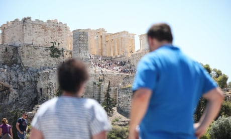 Los turistas miran hacia el antiguo Templo del Partenón en la colina de la Acrópolis de Atenas.