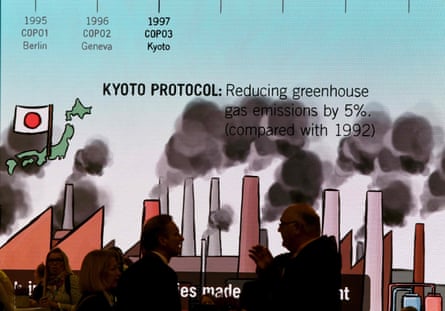 Visitors chat in front of a giant screen featuring information related to the Kyoto protocol at Cop23 in Bonn, Germany