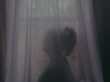 Silhouette of a woman behind gauzy curtains.